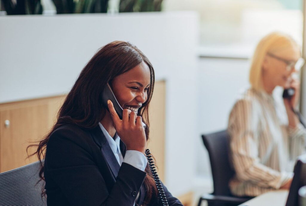 Telemarketingmedarbetare pratar med en kund via telefon på ett modernt kontor.